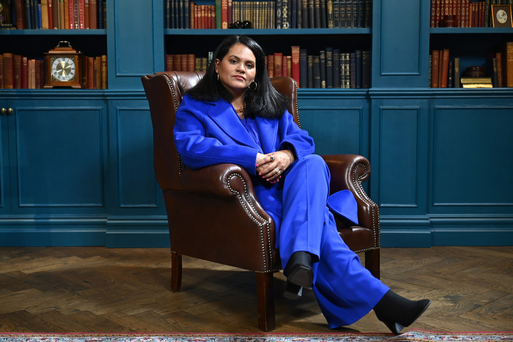 סנדרה דיאז-טווין בחליפה כחולה יושבת עם רגליה שלובות על הבוגדים